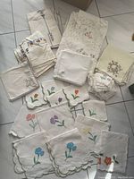 Full overview showing assortment of embroidered, crochet, and tatted vintage linens including table cover, napkins, and doilies