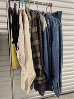 Photo showing several western-styled long-sleeve shirts hanging, including plaid and denim, and jean skirts.