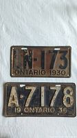 Two vintage Ontario license plates side by side on a white fabric surface.