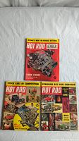 Photo showing all three Hot Rod magazines from 1961 laid out on white surface, covers visible with distinct colorful automotive-themed illustrations