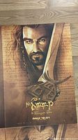 Close-up of The Hobbit poster showing Thorin Oakenshield with sword, sepia tones and Elvish script
