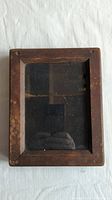Full front view of the antique wooden picture frame showing rectangular shape, dark wood, glass front, and visible aging.