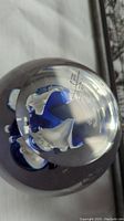 Close-up photo of the base of the paperweight showing the artist's signature and edition number etched on the glass.