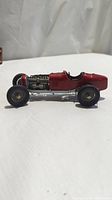 Side view of the Casadio model race car showing profile, red body, front wheels and exposed detailed metallic engine