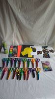 Lot laid out on white backdrop showing 19 pairs of colorful craft scissors with different blade patterns, assorted stickers, green craft gravel container, glue stick, and paper tabs.