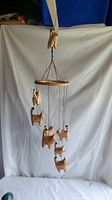 Full view of wooden cat mobile hanging with white backdrop.