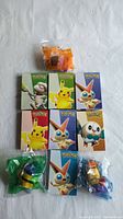 Overview photo showing 7 boxed Pokemon toys and 3 Minions in sealed plastic bags, all new.