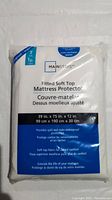 Front view of Mainstays brand fitted soft top mattress protector packaging showing size and product details.