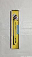 Photo of the front side of the boxed selfie stick showing the product image and yellow packaging.
