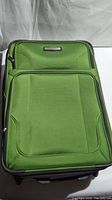 Close up of extra large green Tracker suitcase front with visible brand label