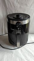 Full view of the Tfal air fryer showing its cylindrical shape and handle on white background.