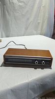 Full front and top perspective showing rectangular vintage tuner with wood grain finish and power cord at the back.
