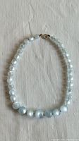 Full view of vintage moonglow bead necklace laid flat showing round beads and sterling clasp.