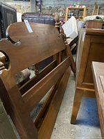 Side view of antique walnut bed frame showing headboard and footboard posts with carved pineapple finials and horizontal mattress support boards.