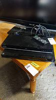 Two black Blu-ray Disc players stacked, one Samsung on top, one Sony below, with a remote control on top. Shows physical condition and accessories.