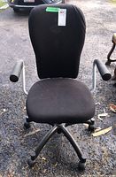 Front view of the Ikea Nomnell desk chair showing the black fabric upholstery, armrests, and wheeled base.