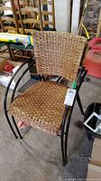 Full view of one rattan chair with a metal frame in a storage area.
