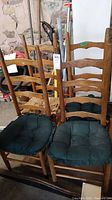 Four wooden ladder back chairs with cord seats and green seat cushions, showing damage to cord seats.
