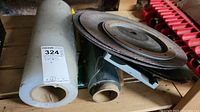 Two rolls of plastic wrap next to three cutting disks on a wooden surface, light marks and usage visible