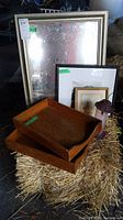 Photo showing mirror, two pictures, wooden trays, and small bird feeder on hay bale