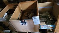 Three cardboard boxes, one with plastic hosing and two with metal hardware parts.