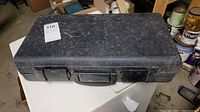 Closed black hard plastic carrying case labeled 310, dusty and used appearance