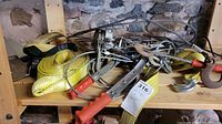 Photo of nylon straps and metal cable winches on wooden shelf with stone wall background.