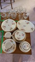 Photo showing the full china set including plates, cups, saucers, covered sugar bowl, and glass stemware