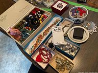 Wide shot of assorted costume jewelry including beads, pins, necklaces, and earrings in boxes and dishes on a table.