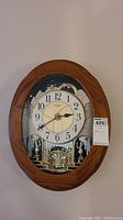 Frontal view of the complete oval clock in faux woodgrain frame