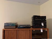 Two turntables and stack of audio/video components on wooden console
