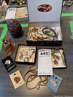 Photo showing the full lot on table with trinket box, decorative eggs, perfume bottle, and jewelry items scattered.