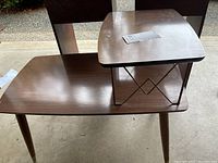 Photo showing the stepped two-level surface of the side table with angled metal supports and tapered wooden legs.