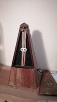 Front view of the vintage wooden mechanical metronome without cover showing pendulum and beat scale.
