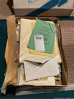 Photo of opened box with loose papers, envelopes, and a green cloth bag labeled 'Foreign Stamp Mixture' showing the general contents of the lot.
