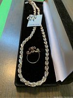 Necklace and ring displayed in black jewelry case with stitched interior.