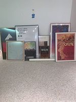 Ten framed art and print pieces lined up against a wall, showing different sizes and frame styles.