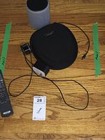 Overview of Bose speaker, carrying case, power adapter, audio cable, and remote on wooden floor.