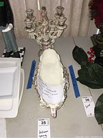 Porcelain serving dish and ornate candelabra placed on a table, showing overall design and scale.