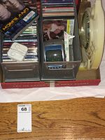 Photo showing the mesh organizer with CDs, Homeland DVD box set, small analog TV, earphones, and large retro clock beside it.