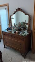 Full view of wood dresser showing large attached mirror and various decorative items on top.