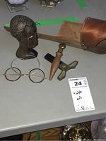 Photo showing vintage male bust, round eyeglasses, and French wine corker on tabletop