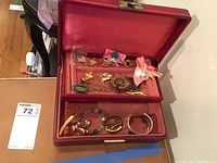 Open red multi-tier jewelry box showing various gold tone and beaded jewelry pieces inside.