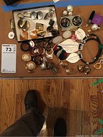 View of assorted jewelry on a wooden surface including earrings, rings, bracelets, and brooches