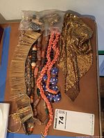 Multiple assorted necklaces arranged on a table showing different styles and materials including beaded, wooden, and metal mesh styles.