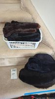 Basket with multiple vintage mink fur pieces including hats and fur strips, plus leather gloves on carpeted stairs