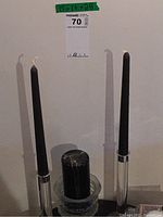 Two black taper candles, one partially burned, one in glass holders; large black pillar candle in glass dish visible