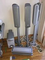 Overview of four satellite speakers on stands, one horizontal center channel speaker, one subwoofer, and cables on floor
