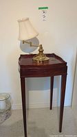 Full view of wood side table with brass lamp on top