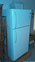 Full view of the white Westinghouse refrigerator with freezer on top, showing its overall condition and placement.
